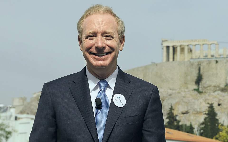 Smiling man in a suit with the Acropolis behind him