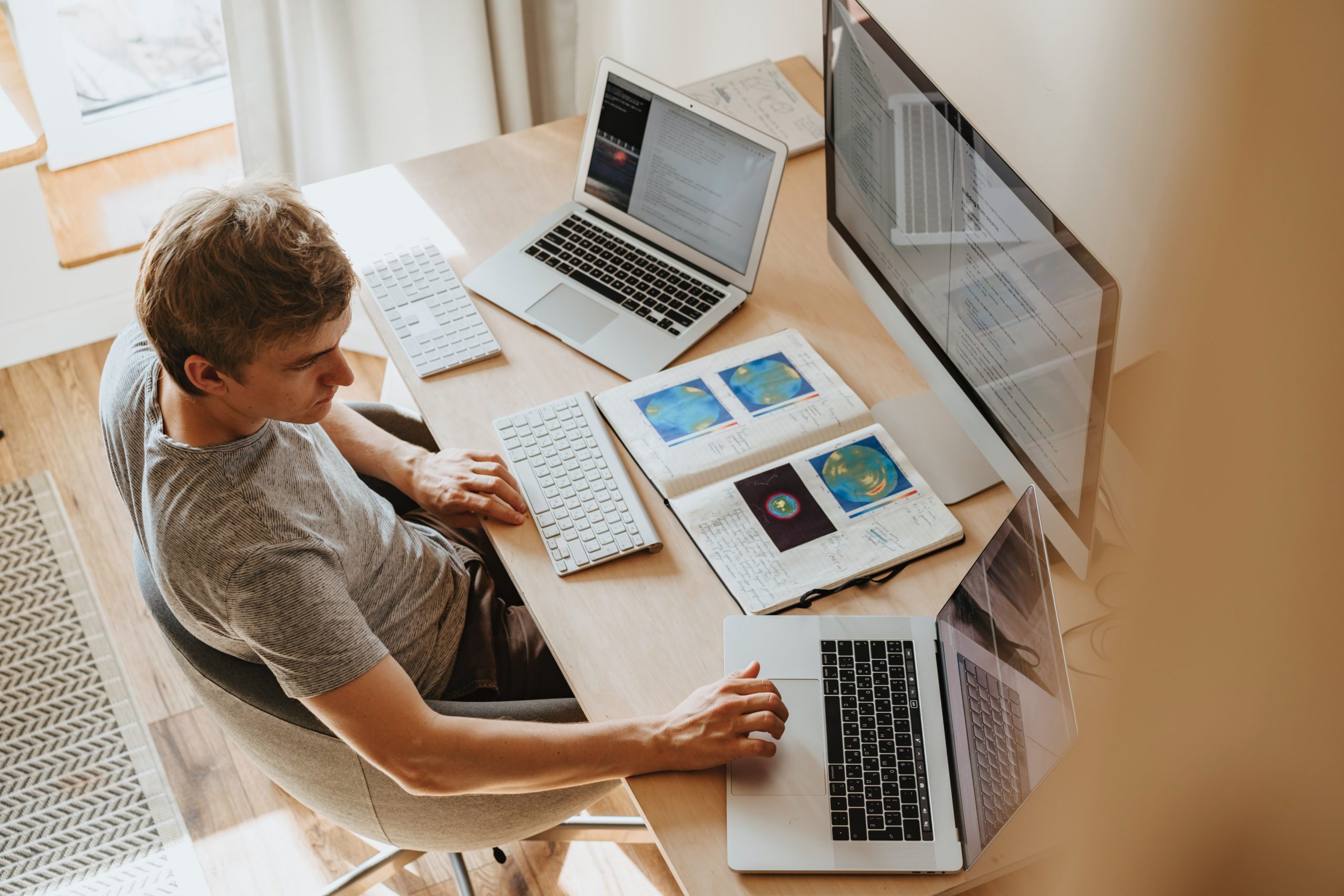 Man working at a desk with laptops and a large monitor