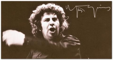Black-and-white photo of a composer conducting, with a handwritten signature
